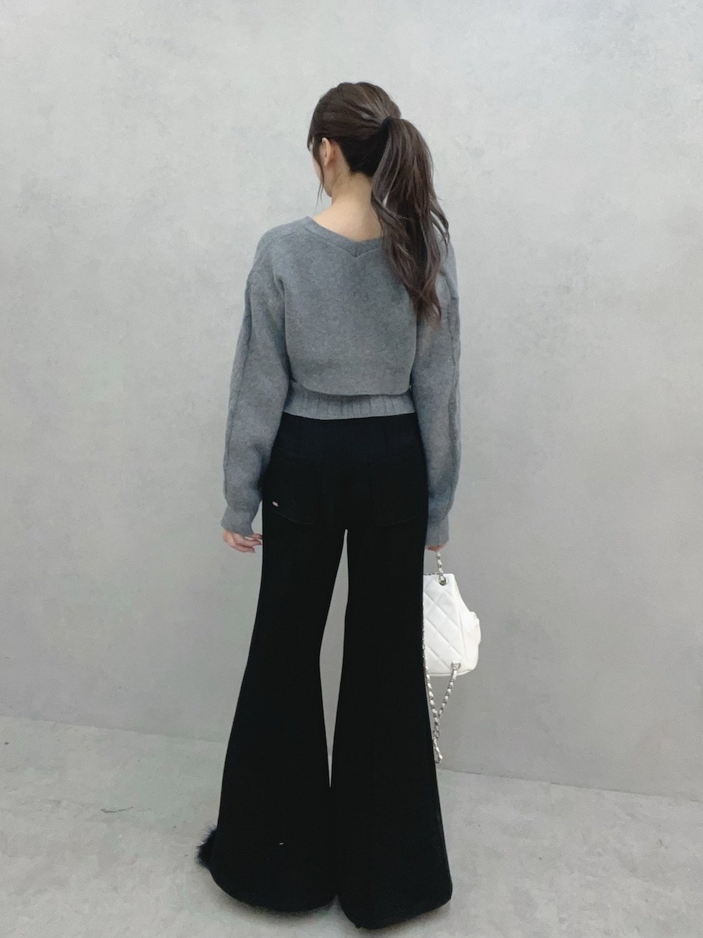 グレー系のニット/セーター、ブラック系のその他パンツ、ホワイト系のバックパック/リュックを着用したレディースの冬コーディネートの5枚目の写真