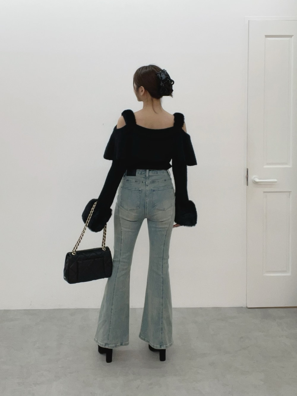 ブラック系のハンドバッグ、ブルー系のデニムパンツ、ブラック系のニット/セーターを着用したレディースの秋コーディネートの5枚目の写真