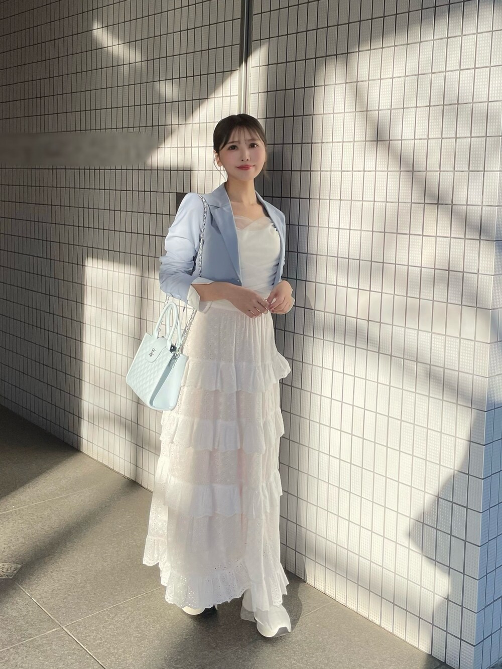 ホワイト系のスカート、ブルー系のハンドバッグ、ホワイト系のブーツを着用したレディースの春コーディネートの3枚目の写真