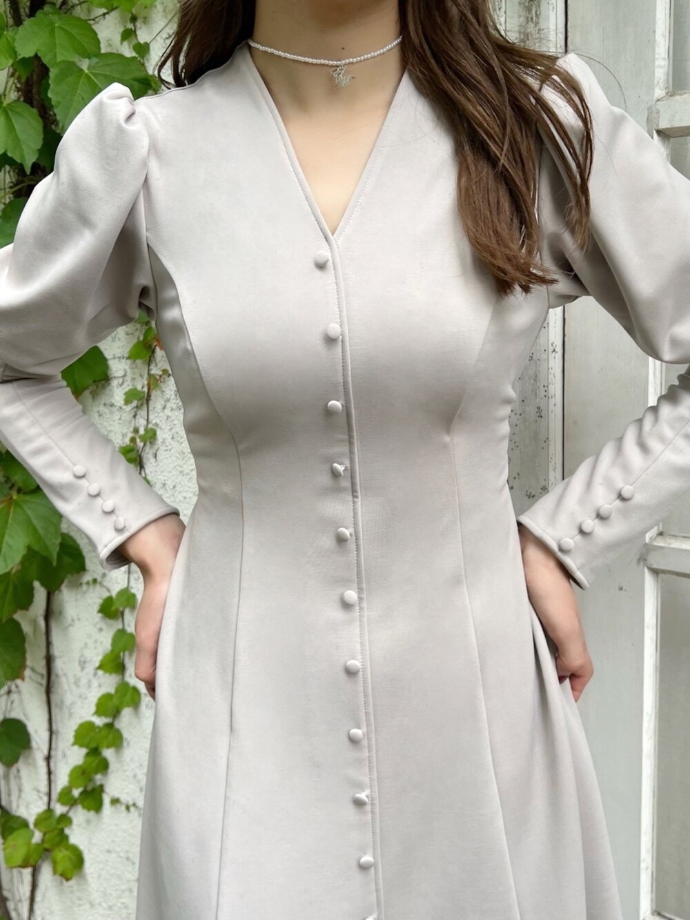 ベージュ系のワンピース、ブラック系のパンプス、ホワイト系のチョーカーを着用したレディースの秋コーディネートの4枚目の写真