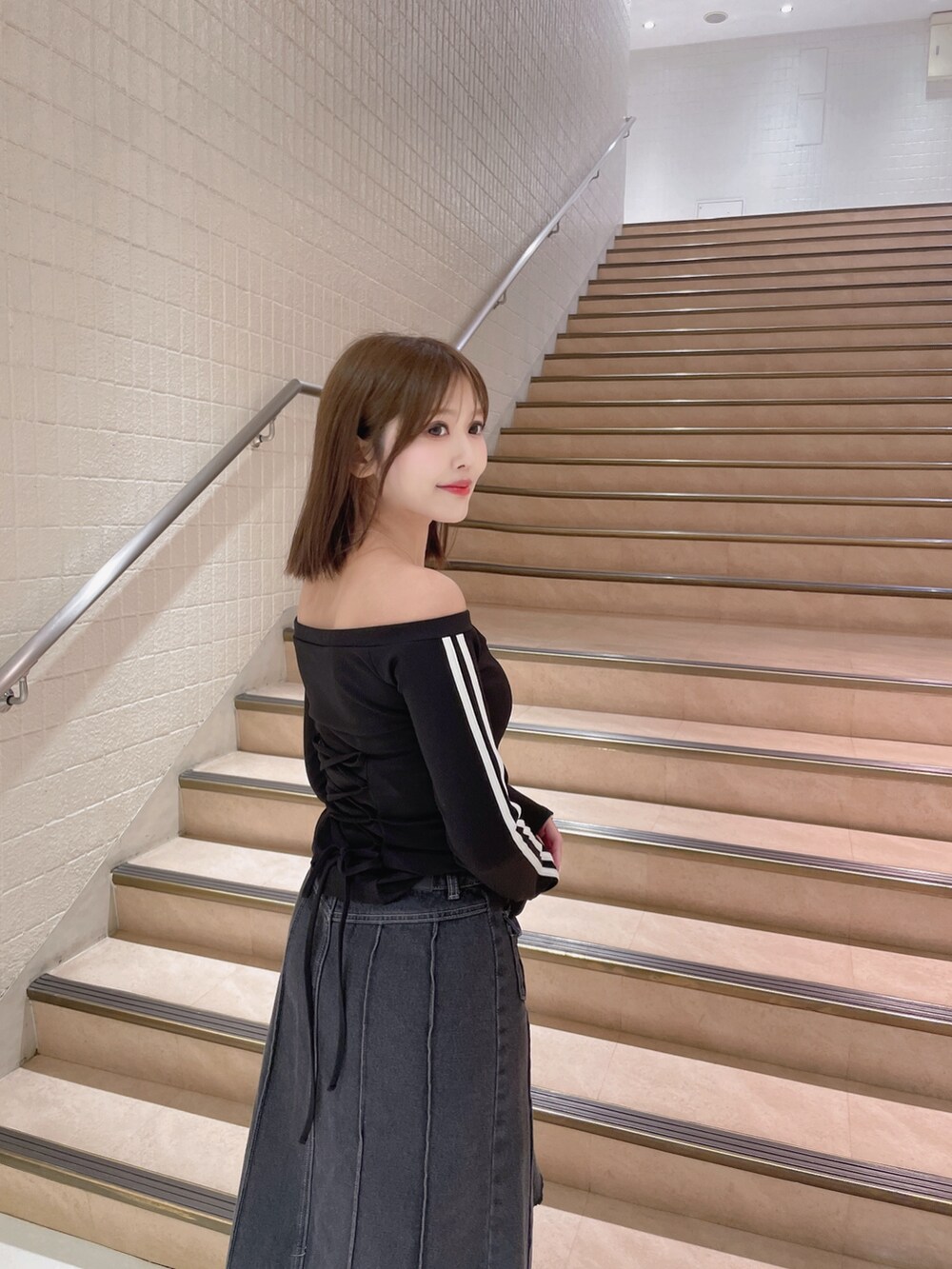 ブラック系のTシャツ/カットソー、ブラック系のデニムスカート、ホワイト系のハンドバッグを着用したレディースの春コーディネートの4枚目の写真