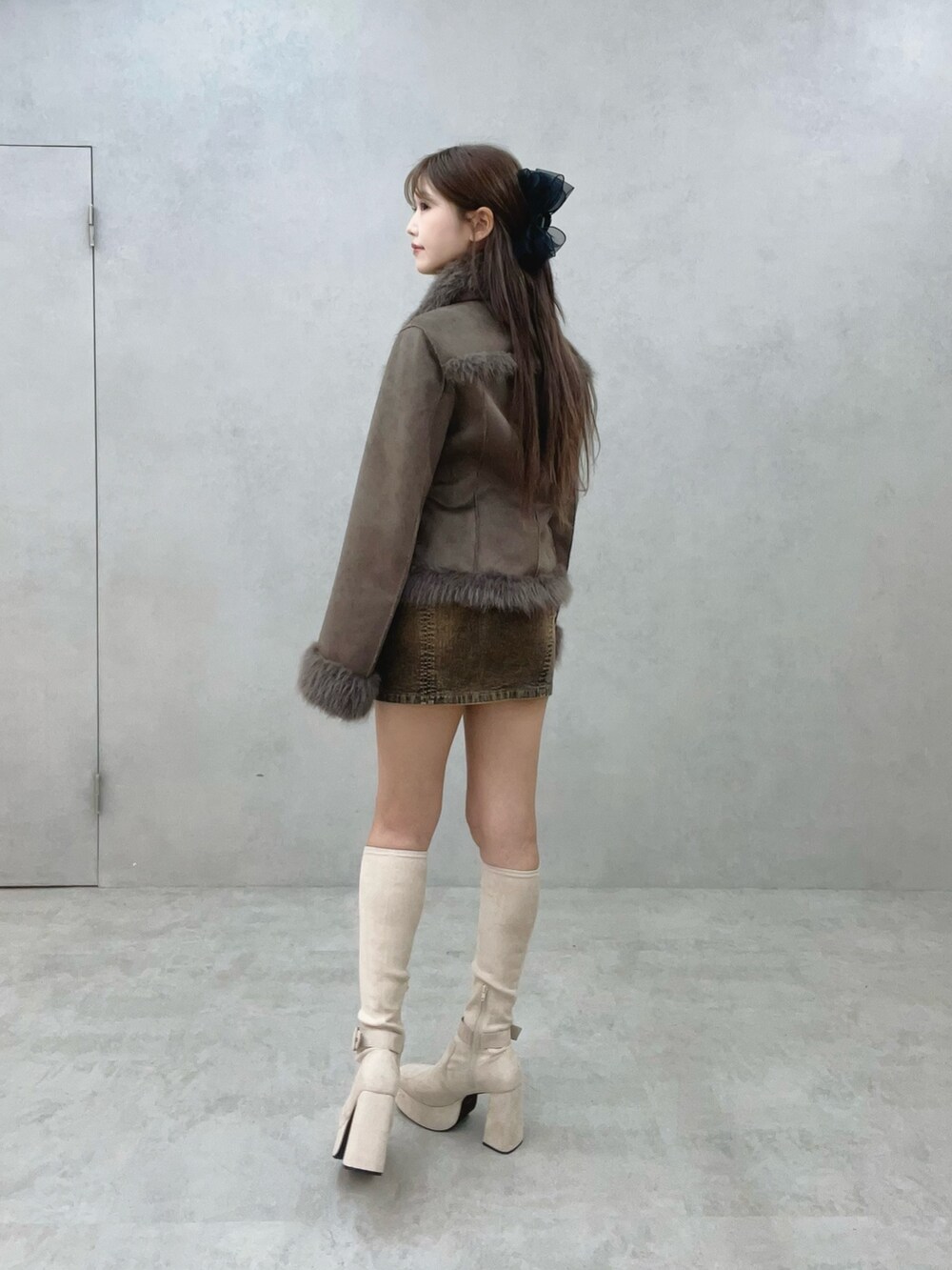 ホワイト系のブーツ、ブラウン系のブルゾン、ブラウン系のデニムスカートを着用したレディースの夏コーディネートの3枚目の写真