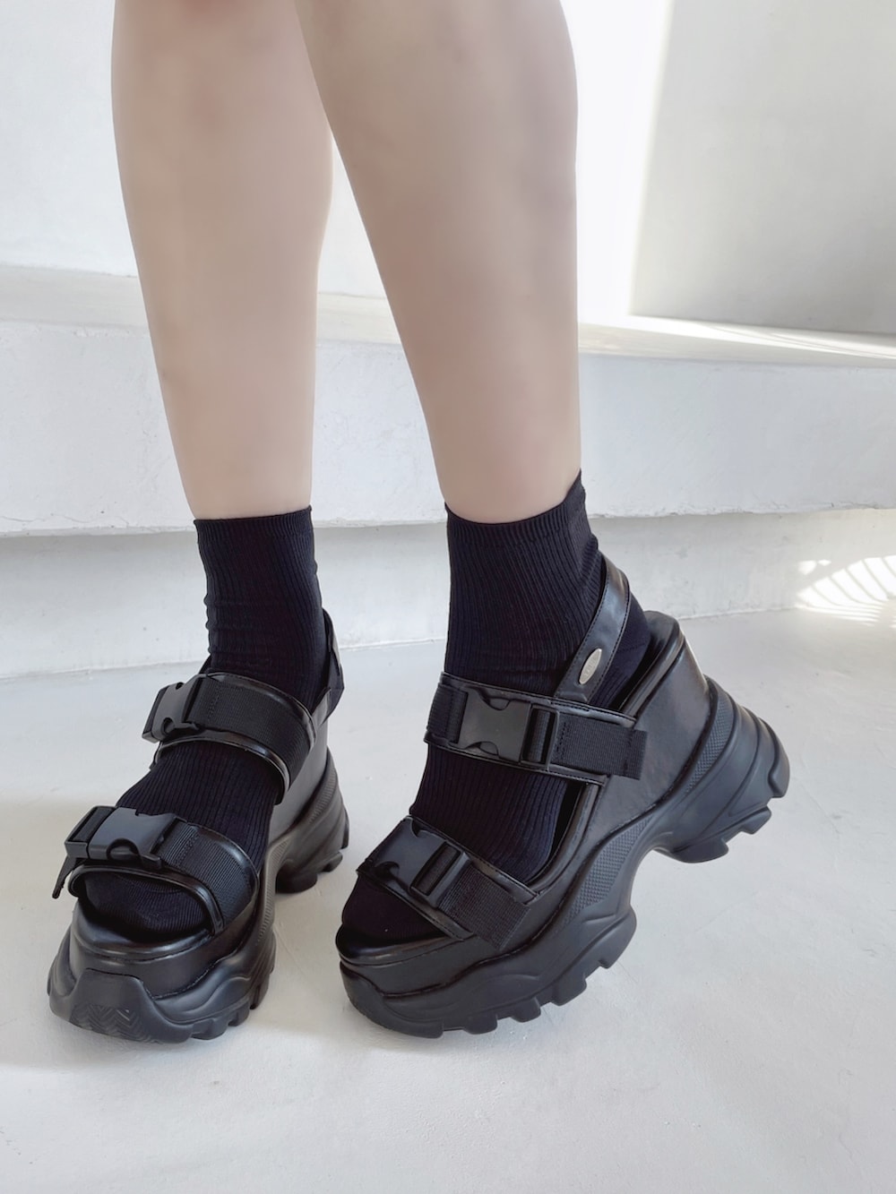 ブラック系のデニムスカート、ブラック系のサンダル、ブラック系のニット/セーターを着用したレディースの冬コーディネートの6枚目の写真