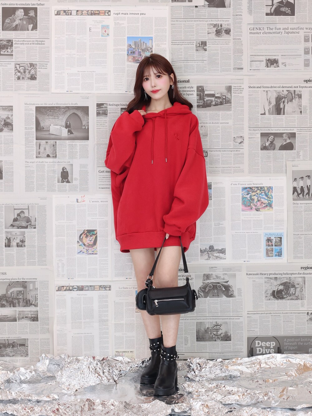 レッド系のパーカー、ブラック系のショルダーバッグ、ブラック系のブーツを着用したレディースの夏コーディネートの6枚目の写真