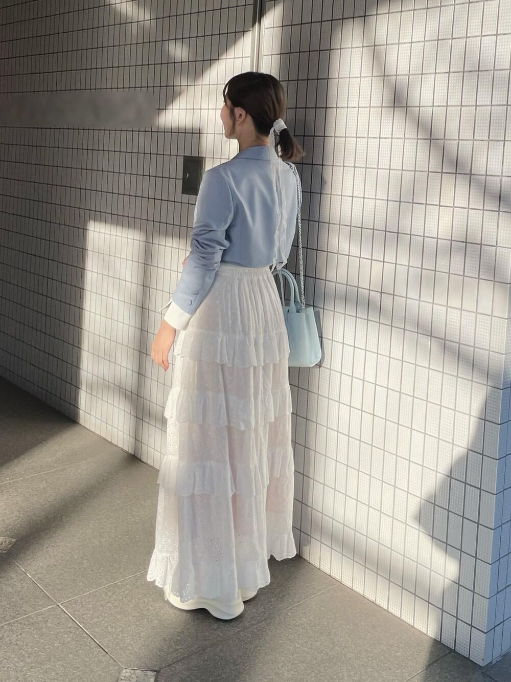 ホワイト系のスカート、ブルー系のハンドバッグ、ホワイト系のブーツを着用したレディースの春コーディネートの6枚目の写真