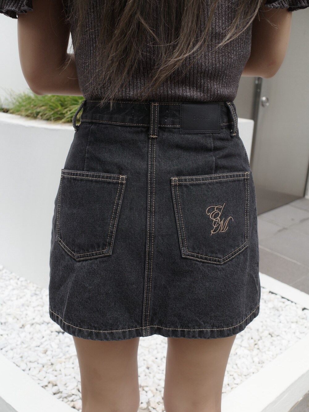 ブラック系のデニムスカート、ブラック系のサンダル、グレー系のTシャツ/カットソーを着用したレディースの夏コーディネートの9枚目の写真