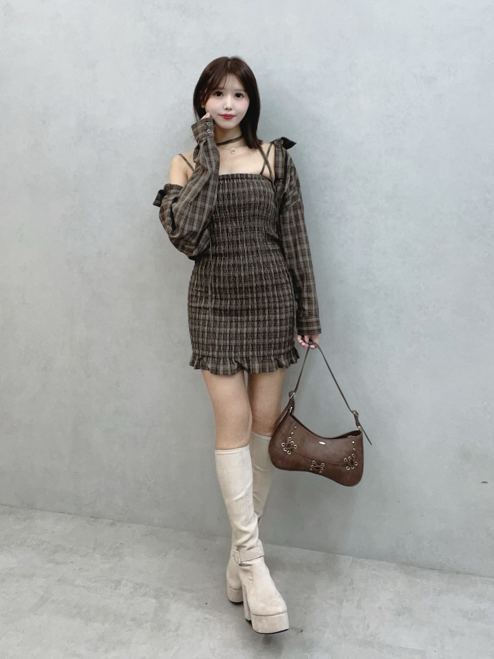 ブラウン系のワンピース、ブラウン系のショルダーバッグ、ホワイト系のブーツを着用したレディースの秋コーディネートの2枚目の写真