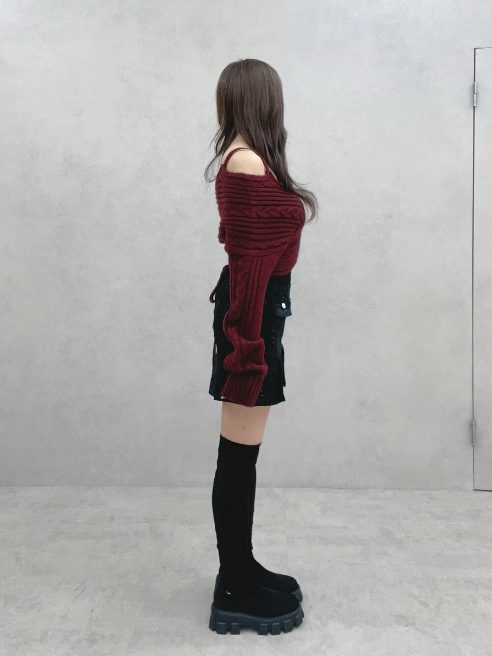 ブラック系のブーツ、ブラック系のスカート、レッド系のニット/セーターを着用したレディースの冬コーディネートの3枚目の写真