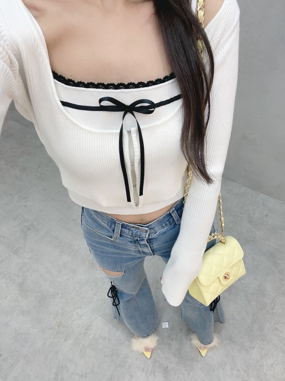 ホワイト系のニット/セーター、イエロー系のサンダル、ブルー系のデニムパンツを着用したレディースの冬コーディネートの8枚目の写真