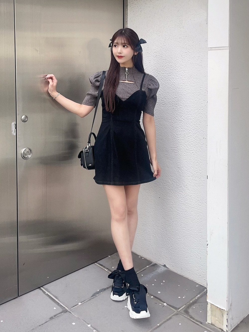 グレー系のニット/セーター、ブラック系のジャンパースカート、その他のサンダルを着用したレディースの春コーディネートの2枚目の写真