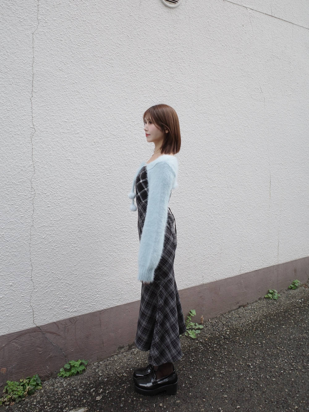 ブルー系のニット/セーター、ホワイト系のハンドバッグ、ブラック系のワンピースを着用したレディースの秋コーディネートの3枚目の写真