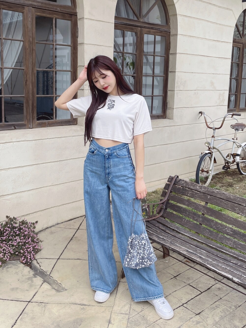 ブルー系のデニムパンツ、シルバー系のハンドバッグ、ホワイト系のTシャツ/カットソーを着用したレディースの春コーディネートの2枚目の写真