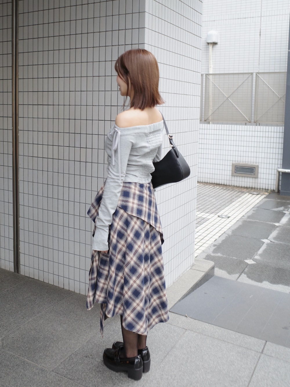 グレー系のTシャツ/カットソー、ブルー系のスカート、ブラック系のショルダーバッグを着用したレディースの秋コーディネートの3枚目の写真