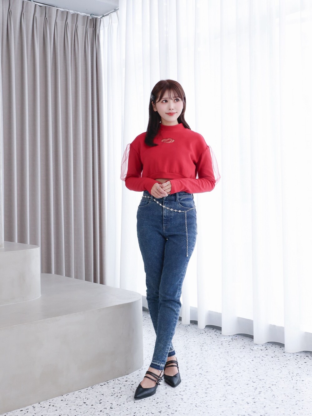 レッド系のスウェット、ブルー系のデニムパンツ、ブラック系のパンプスを着用したレディースの秋コーディネートの2枚目の写真