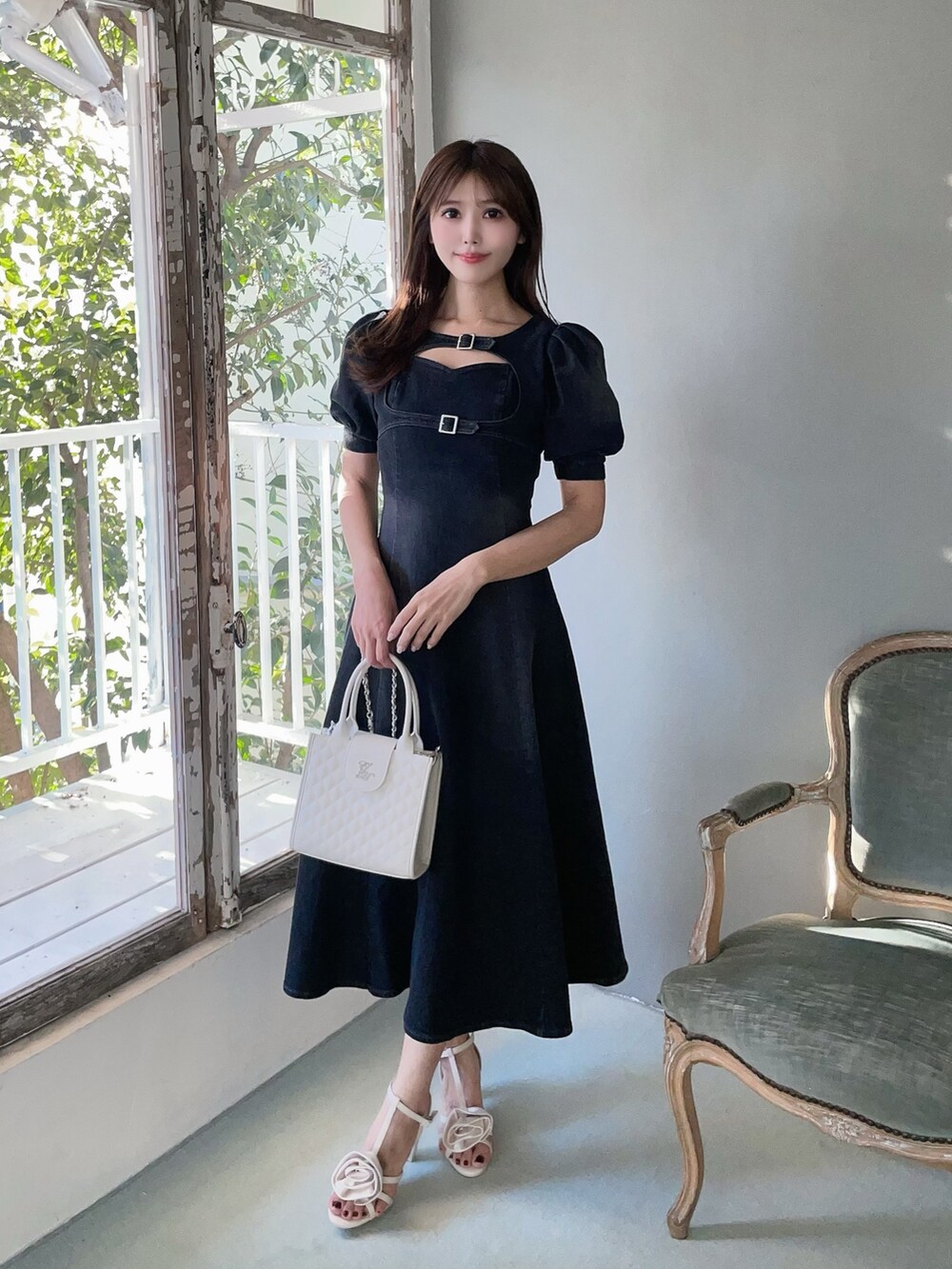 ホワイト系のハンドバッグ、ブラック系のワンピース、ホワイト系のサンダルを着用したレディースの春コーディネートの5枚目の写真