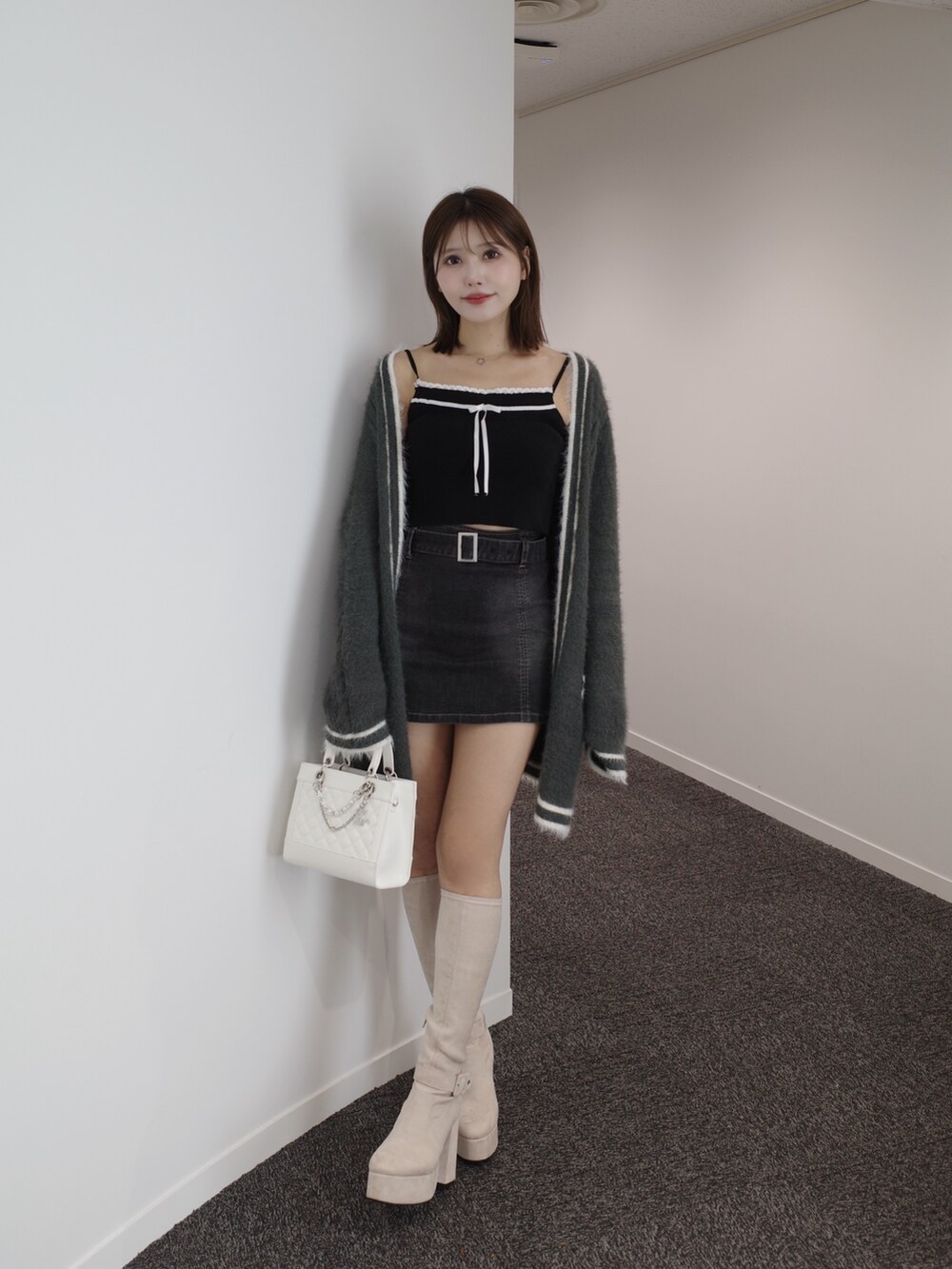 ブラック系のニット/セーター、グレー系のワンピース、ブルー系のデニムスカートを着用したレディースの秋コーディネートの5枚目の写真