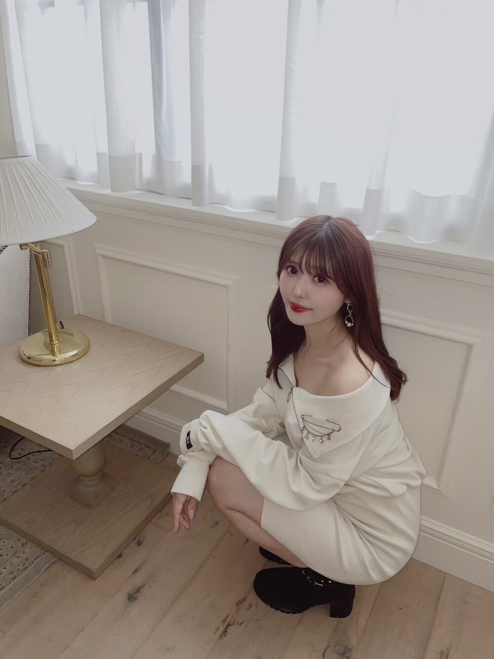 ホワイト系のワンピース、ブラック系のブーツ、シルバー系のブローチ/コサージュを着用したレディースの秋コーディネートの4枚目の写真