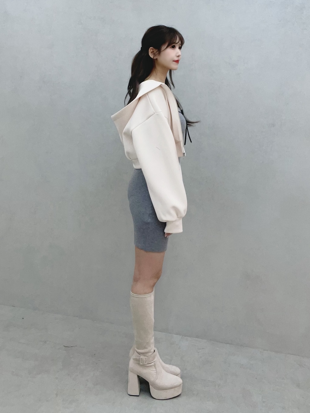 グレー系のワンピース、ホワイト系のパーカー、ホワイト系のブーツを着用したレディースの冬コーディネートの3枚目の写真