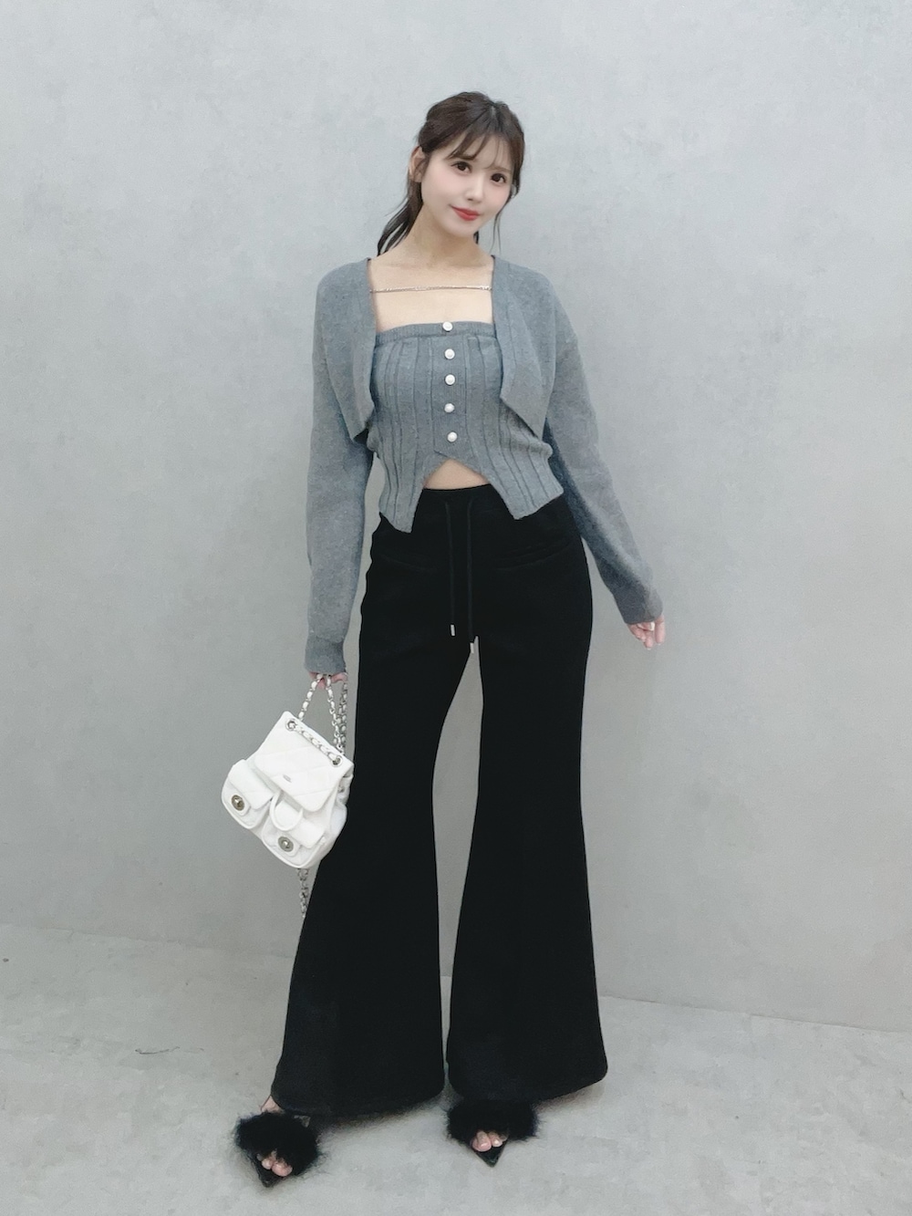 グレー系のニット/セーター、ブラック系のその他パンツ、ホワイト系のバックパック/リュックを着用したレディースの冬コーディネートの2枚目の写真