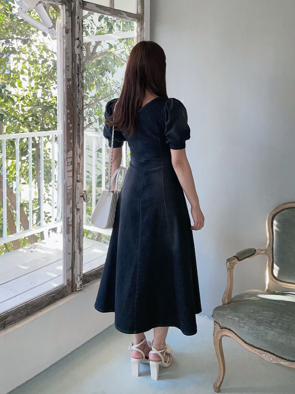 ホワイト系のハンドバッグ、ブラック系のワンピース、ホワイト系のサンダルを着用したレディースの春コーディネートの7枚目の写真