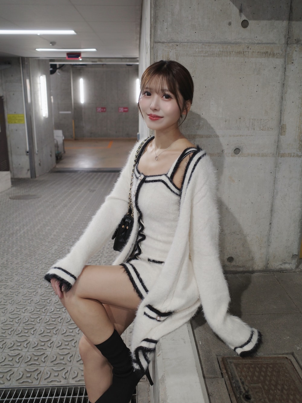 ホワイト系のワンピース、ブラック系のブーツ、ブラック系のハンドバッグを着用したレディースの秋コーディネートの3枚目の写真