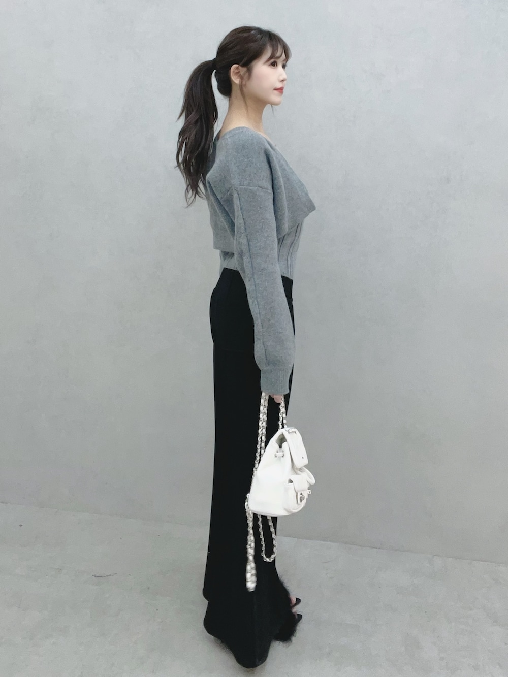 グレー系のニット/セーター、ブラック系のその他パンツ、ホワイト系のバックパック/リュックを着用したレディースの冬コーディネートの4枚目の写真