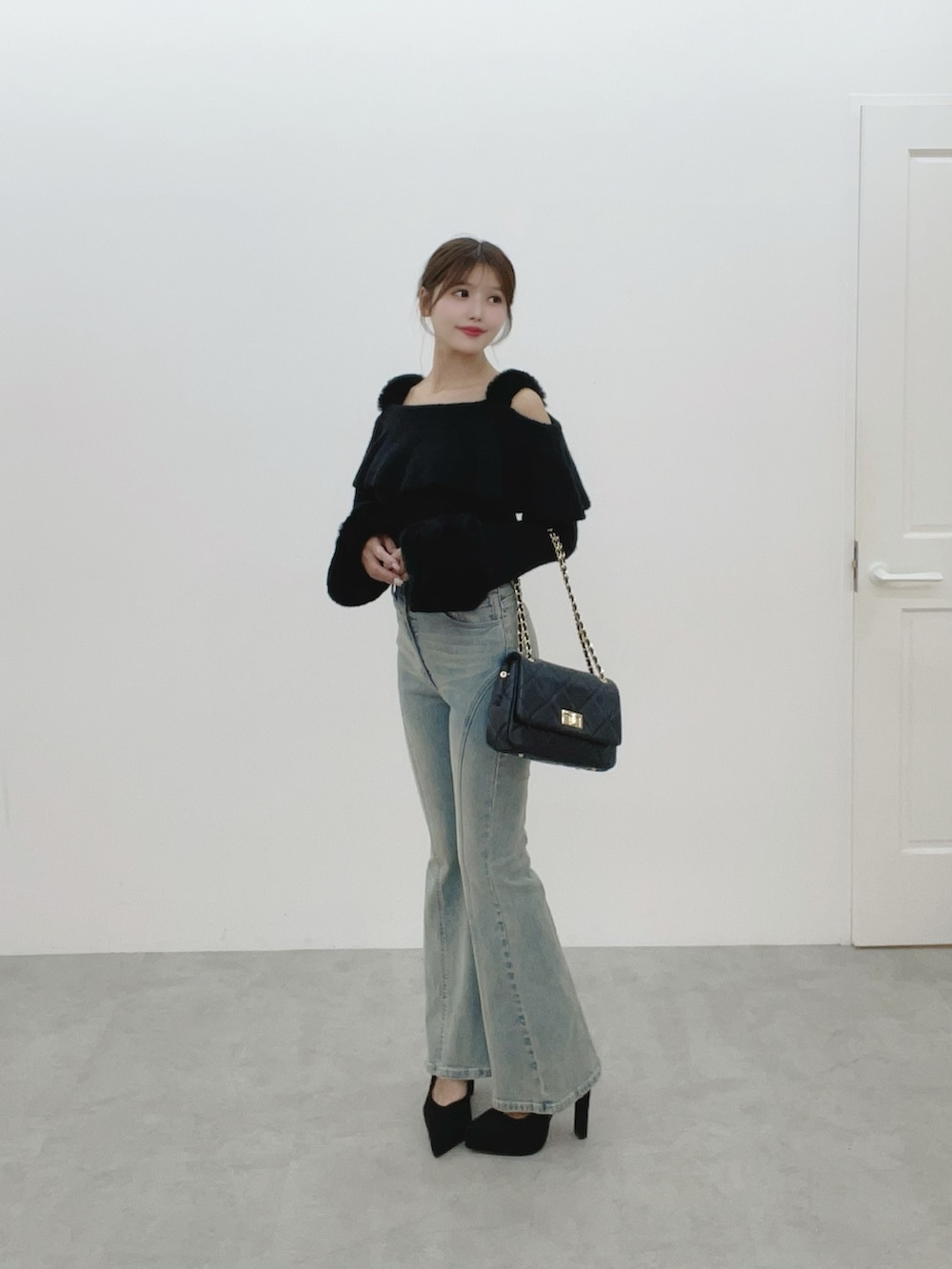 ブラック系のハンドバッグ、ブルー系のデニムパンツ、ブラック系のニット/セーターを着用したレディースの秋コーディネートの2枚目の写真