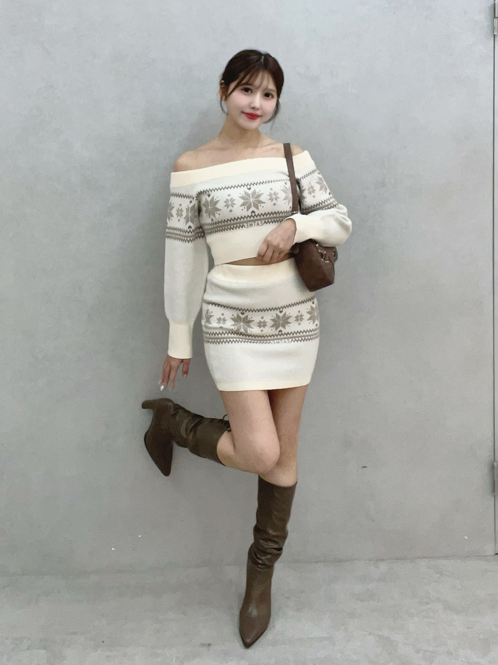 ホワイト系のニット/セーター、ホワイト系のスカート、ブラウン系のブーツを着用したレディースの秋コーディネートの2枚目の写真