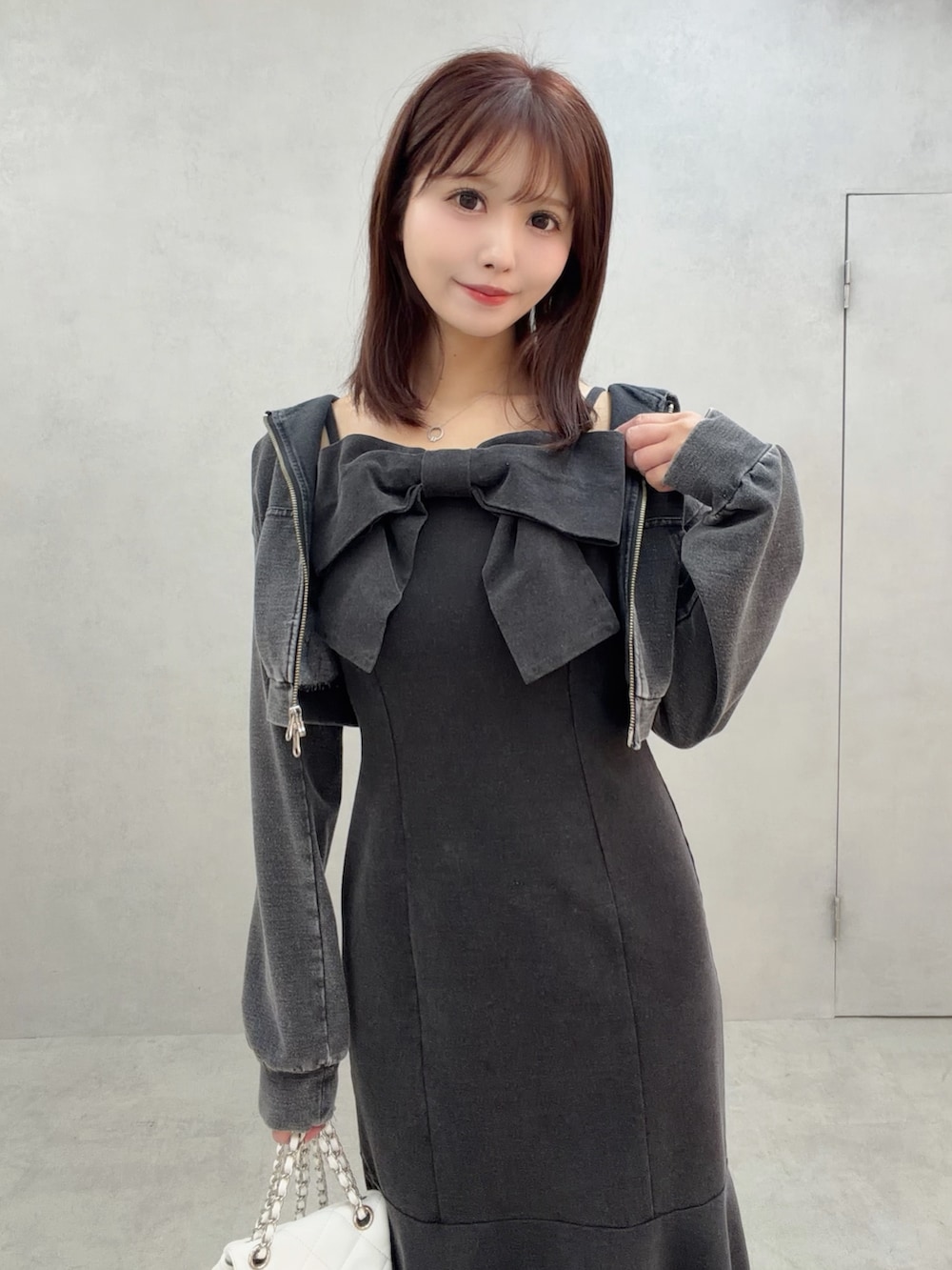 ブラック系のワンピース、ホワイト系のサンダル、ホワイト系のバックパック/リュックを着用したレディースの冬コーディネートの6枚目の写真