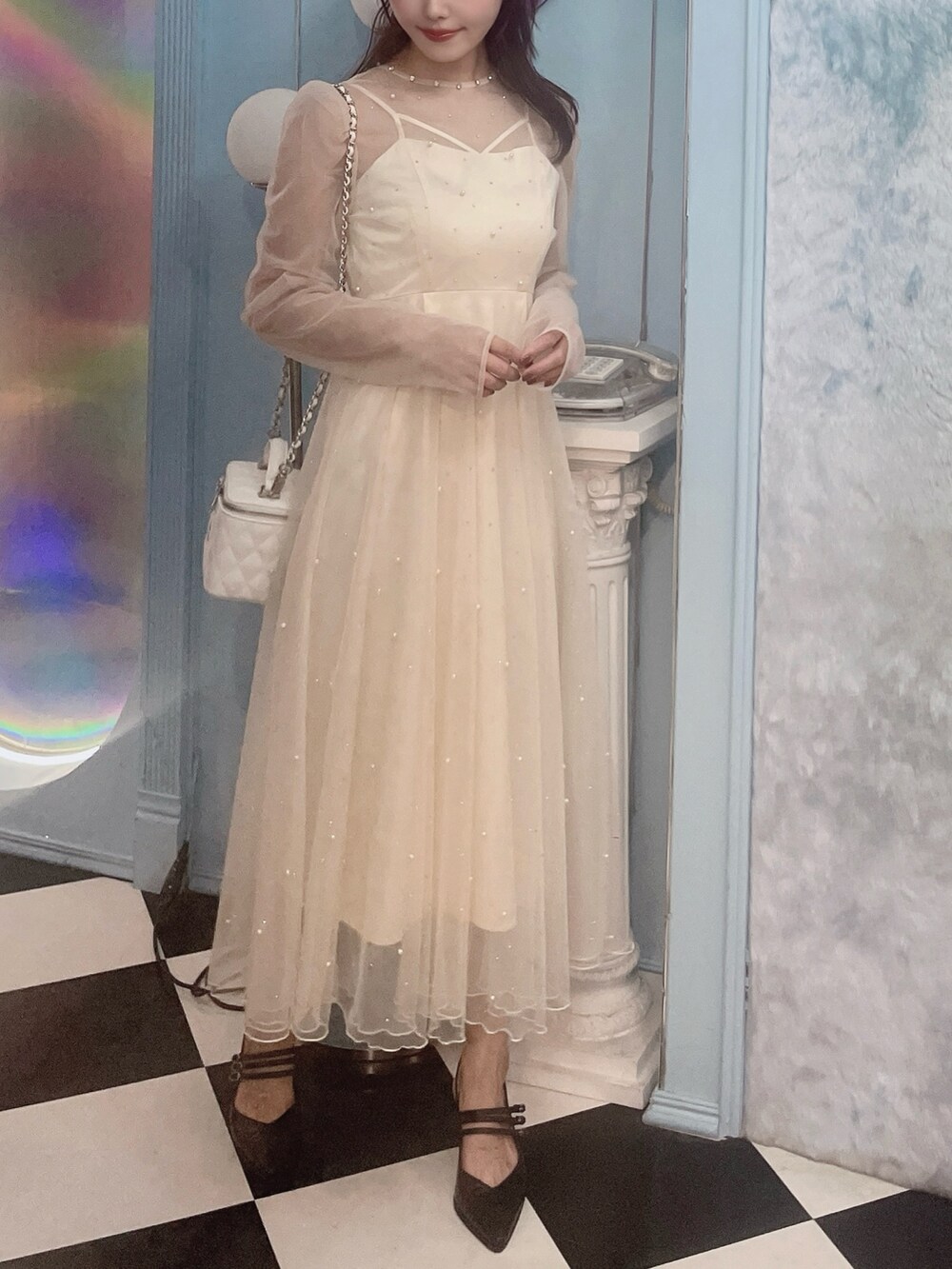 ホワイト系のワンピース、ブラック系のパンプス、ホワイト系のハンドバッグを着用したレディースの秋コーディネートの5枚目の写真