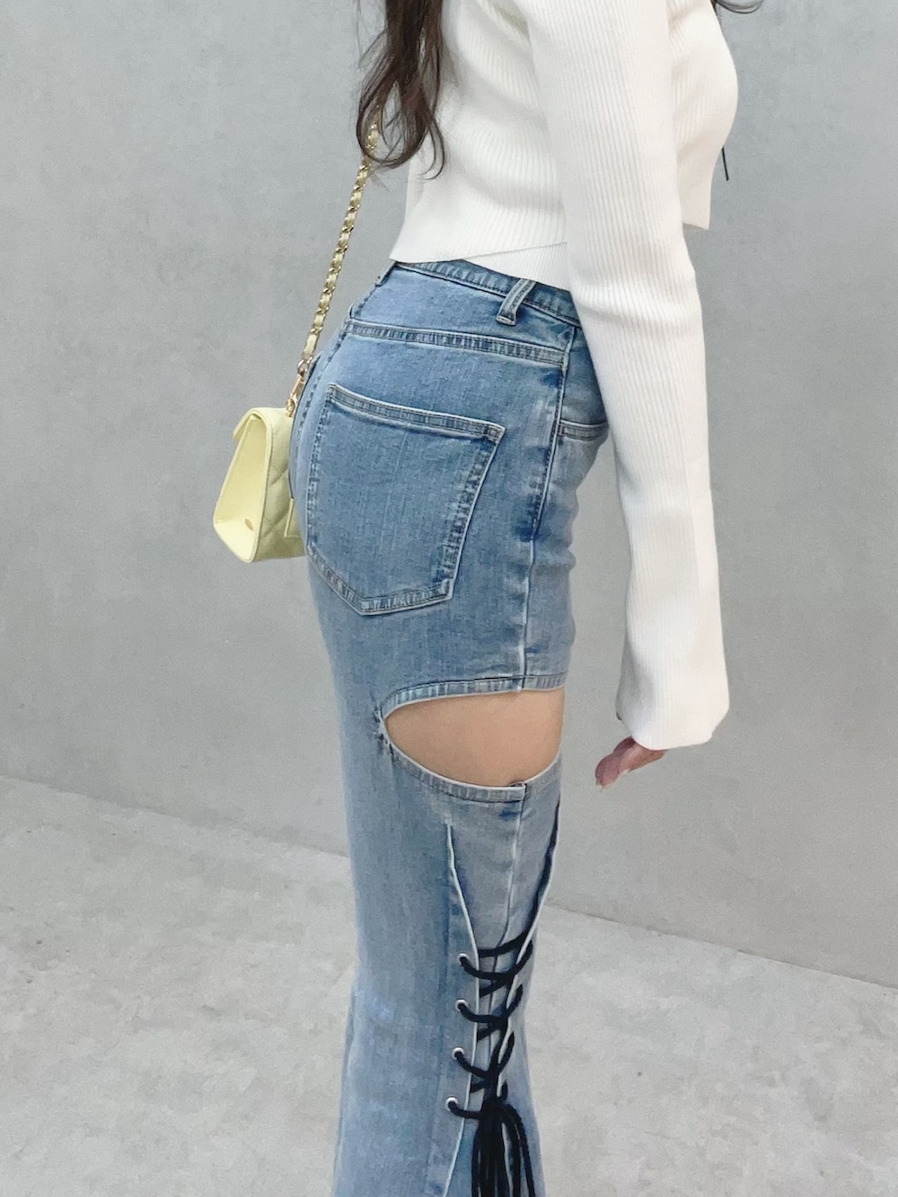 ホワイト系のニット/セーター、イエロー系のサンダル、ブルー系のデニムパンツを着用したレディースの冬コーディネートの6枚目の写真