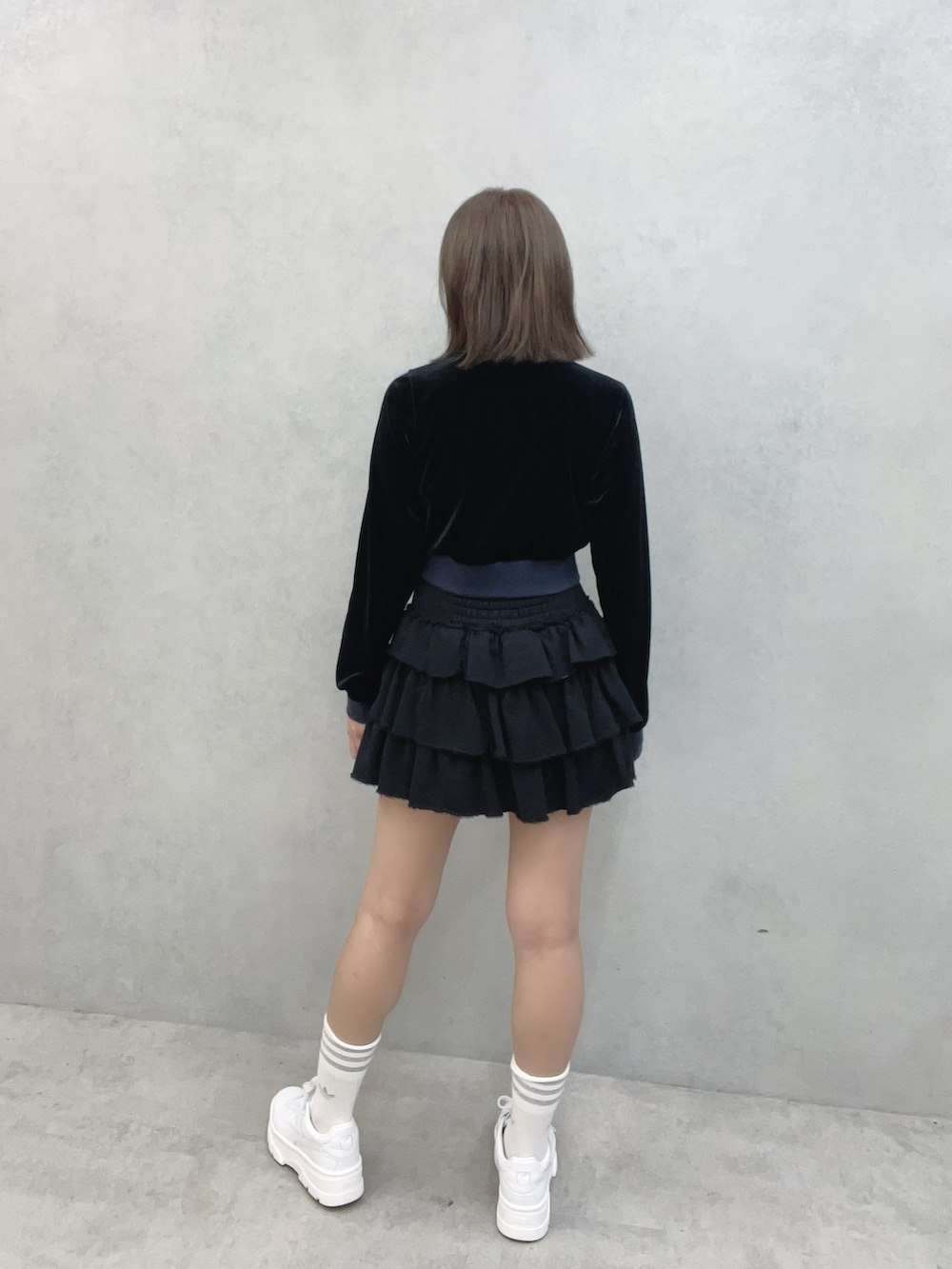 ブラック系のブルゾン、ブラック系のスカート、ホワイト系のスニーカーを着用したレディースの秋コーディネートの5枚目の写真