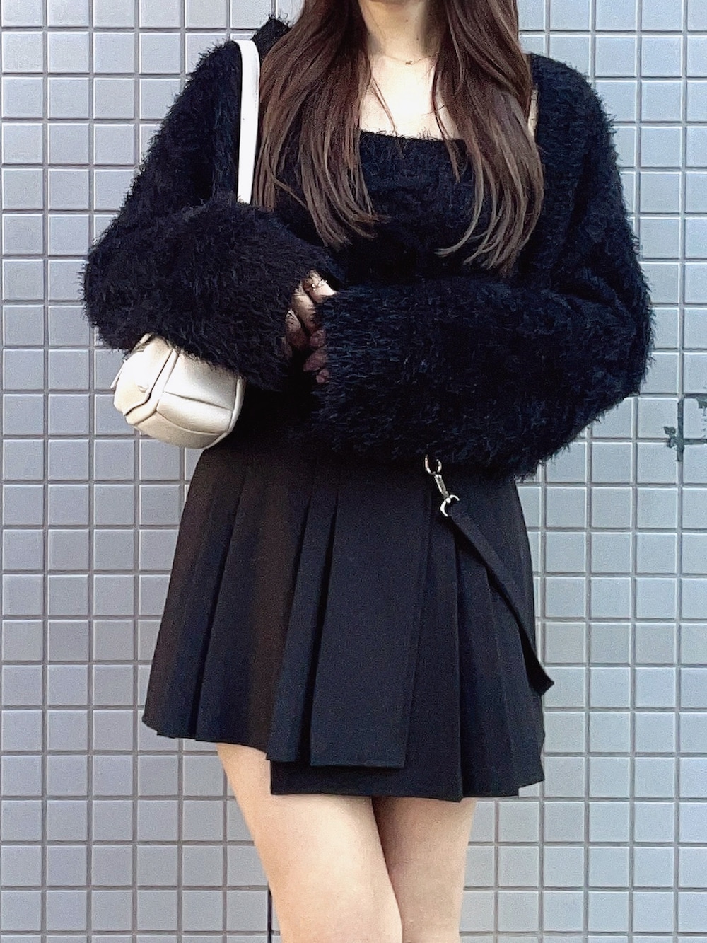 ブラック系のカーディガン/ボレロ、ブラック系のスカート、ホワイト系のブーツを着用したレディースの冬コーディネートの2枚目の写真