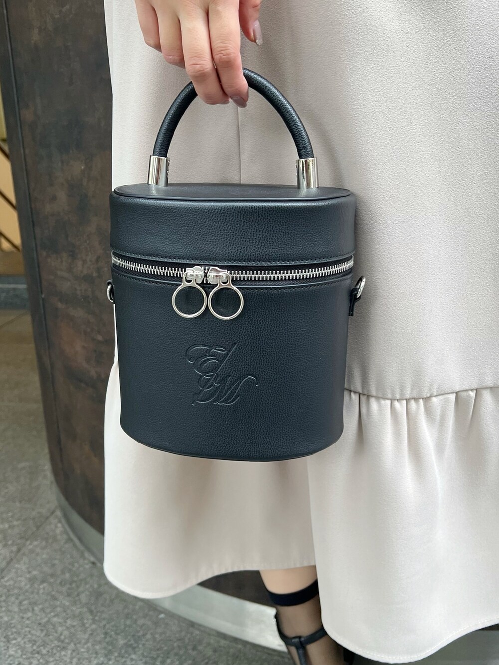 ブラック系のハンドバッグ、ベージュ系のワンピース、ブラック系のサンダルを着用したレディースの春コーディネートの6枚目の写真