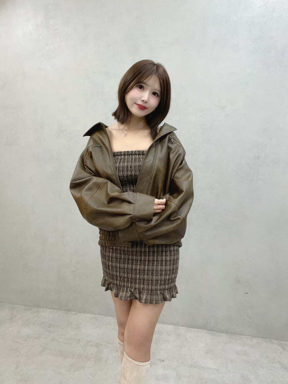 ブラウン系のワンピース、ブラウン系のブルゾン、ホワイト系のブーツを着用したレディースの秋コーディネートの5枚目の写真