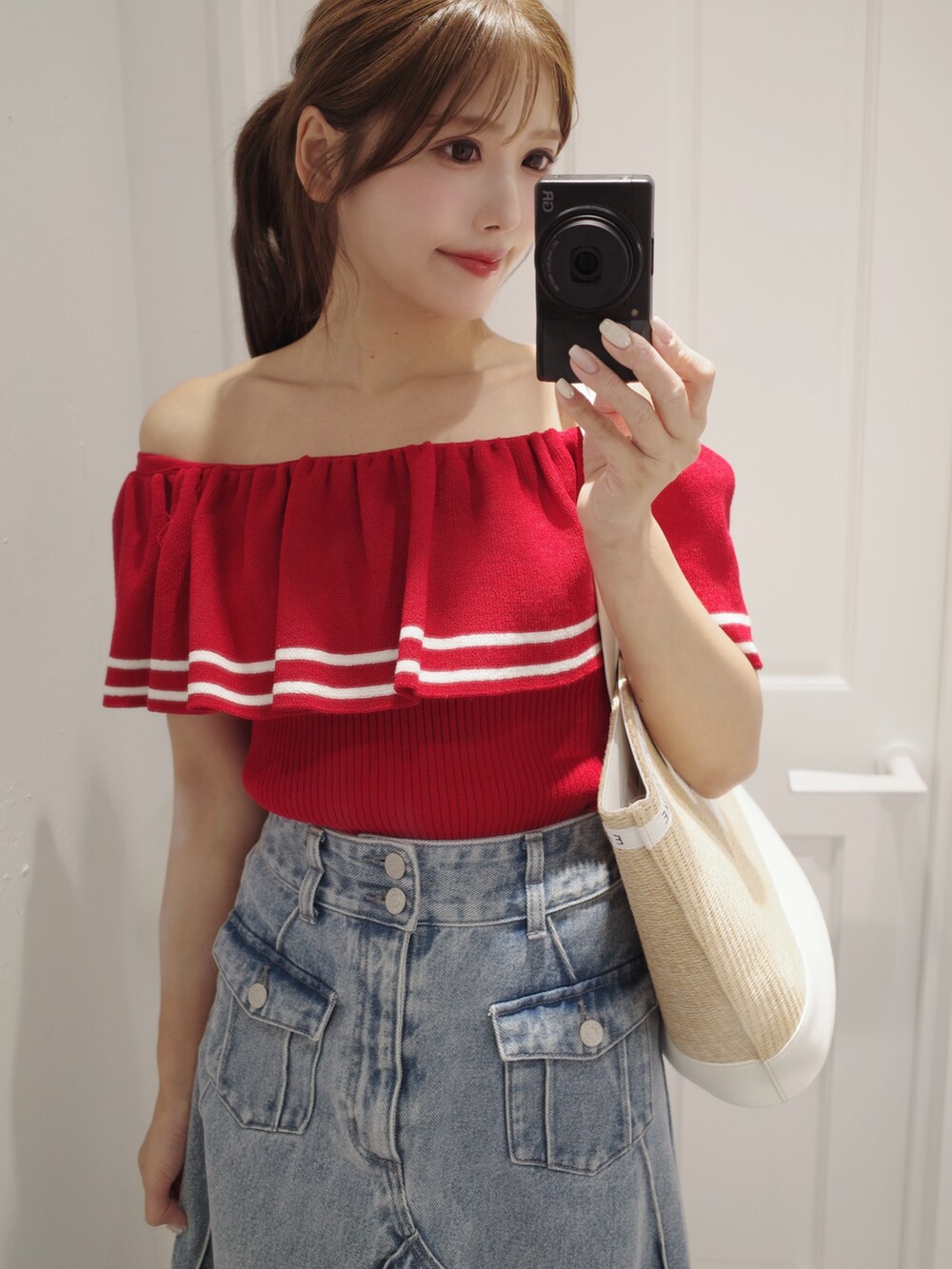レッド系のニット/セーター、ホワイト系のトートバッグ、ブルー系のデニムスカートを着用したレディースの夏コーディネートの4枚目の写真