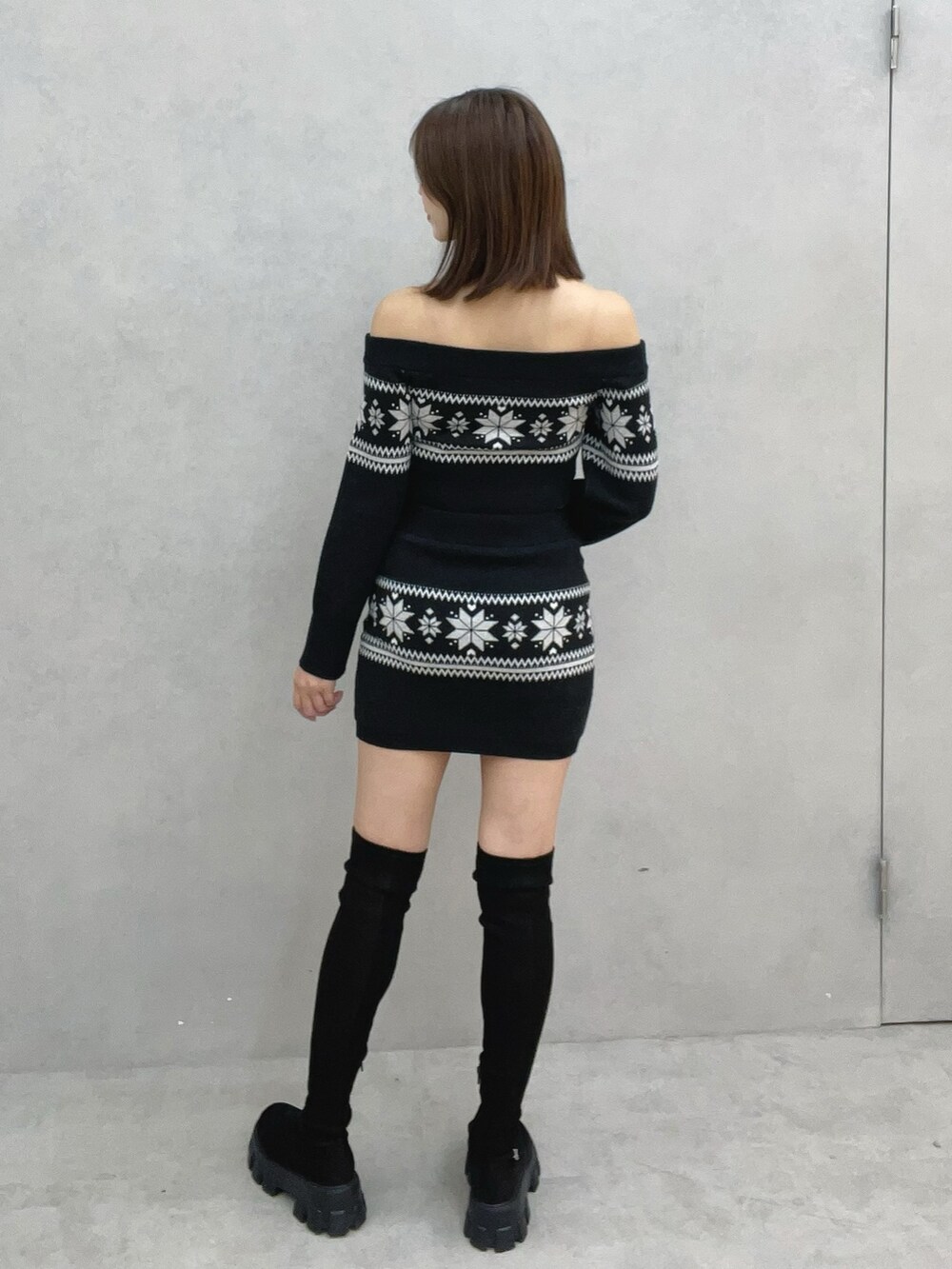 ブラック系のニット/セーター、ブラック系のスカート、ブラック系のブーツを着用したレディースの秋コーディネートの7枚目の写真