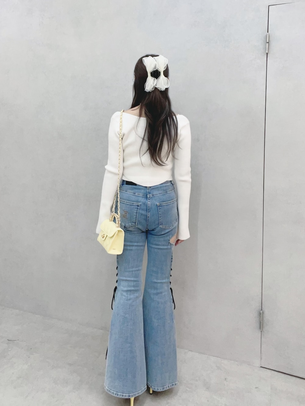 ホワイト系のニット/セーター、イエロー系のサンダル、ブルー系のデニムパンツを着用したレディースの冬コーディネートの5枚目の写真