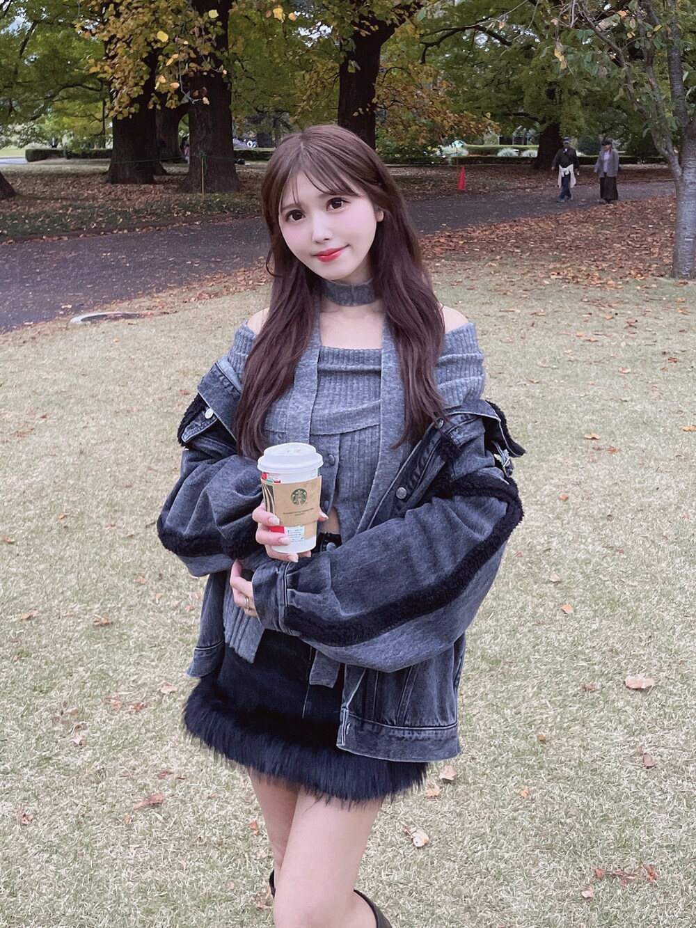 ブラック系のデニムジャケット、グレー系のニット/セーター、ブラック系のデニムスカートを着用したレディースの秋コーディネートの6枚目の写真