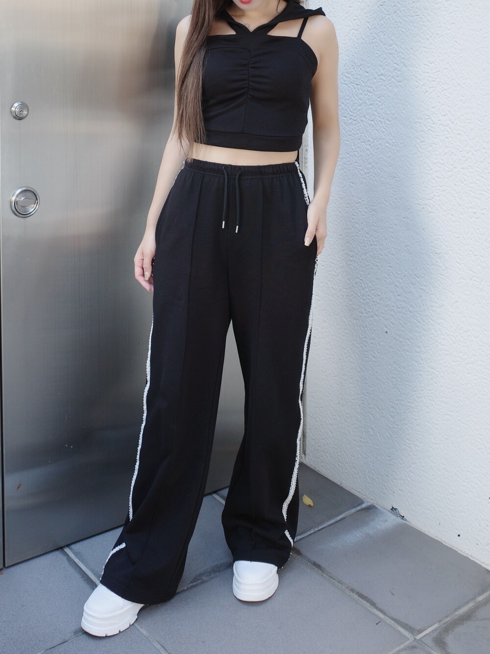 ブラック系のキャミソール、ブラック系のスウェットパンツ、ホワイト系のスニーカーを着用したレディースの夏コーディネートの3枚目の写真