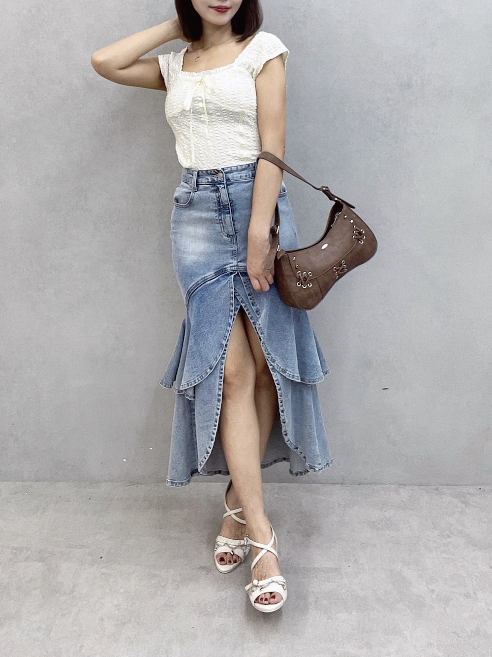ブラウン系のショルダーバッグ、ホワイト系のTシャツ/カットソー、ブルー系のデニムスカートを着用したレディースの秋コーディネートの2枚目の写真
