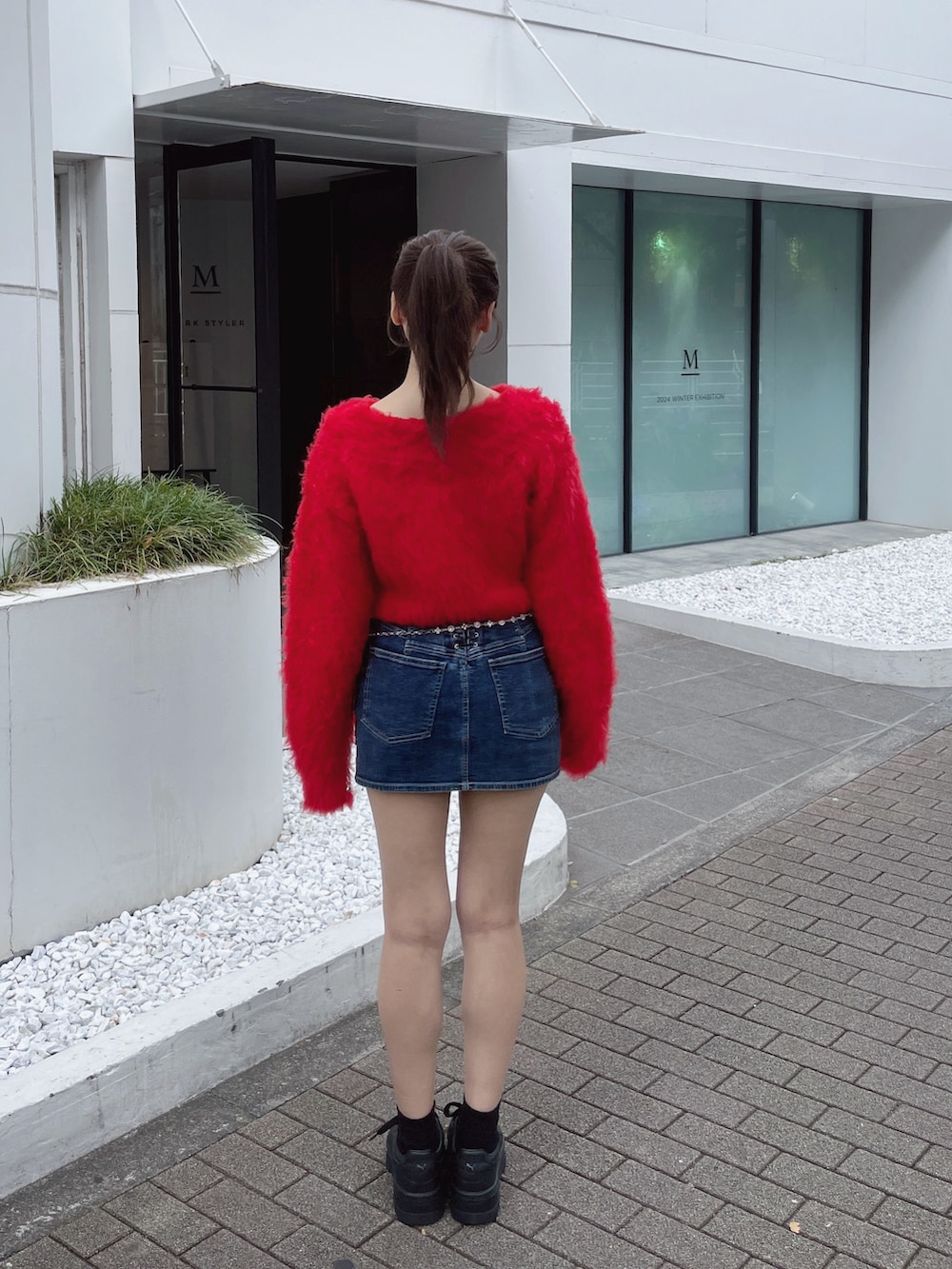 レッド系のニット/セーター、ホワイト系のスニーカー、ブルー系のデニムスカートを着用したレディースの秋コーディネートの6枚目の写真