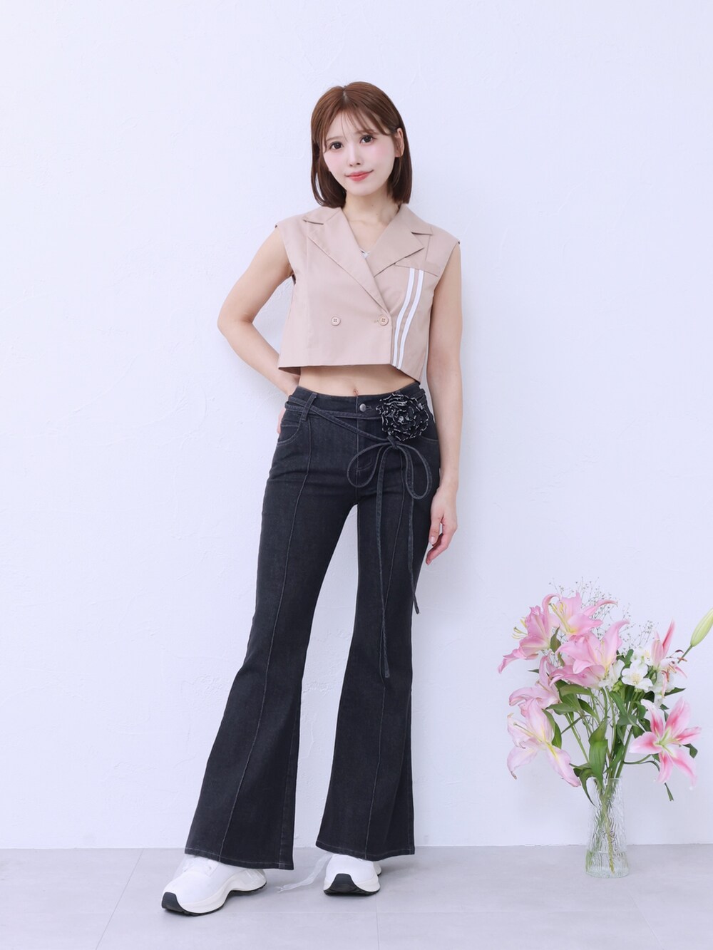 ベージュ系のベスト、ブラック系のデニムパンツ、ホワイト系のブーツを着用したレディースの春コーディネートの2枚目の写真