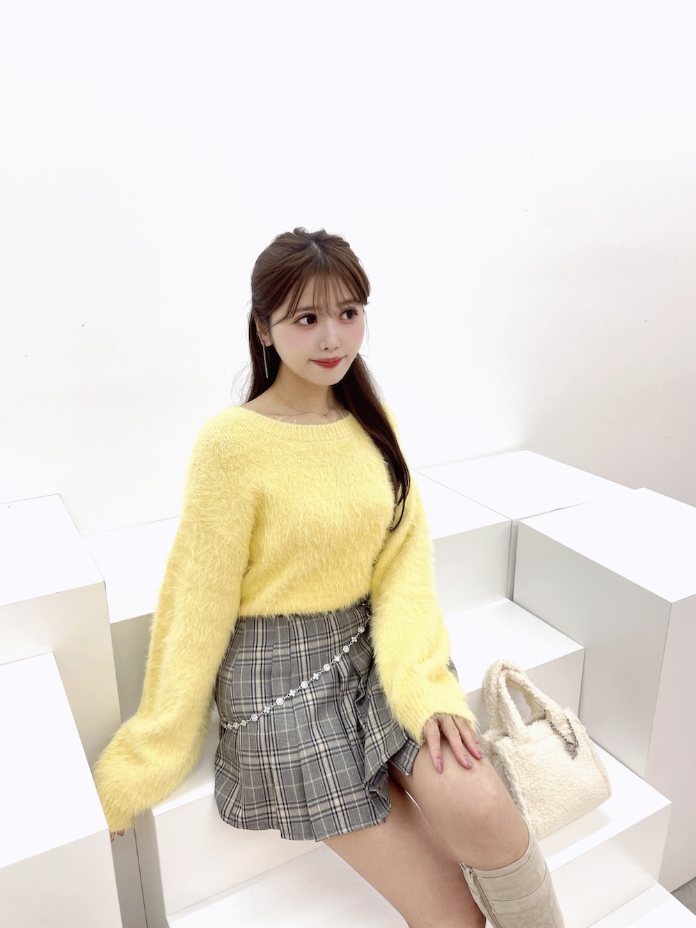 イエロー系のニット/セーター、ホワイト系のブーツ、ホワイト系のハンドバッグを着用したレディースの冬コーディネートの5枚目の写真