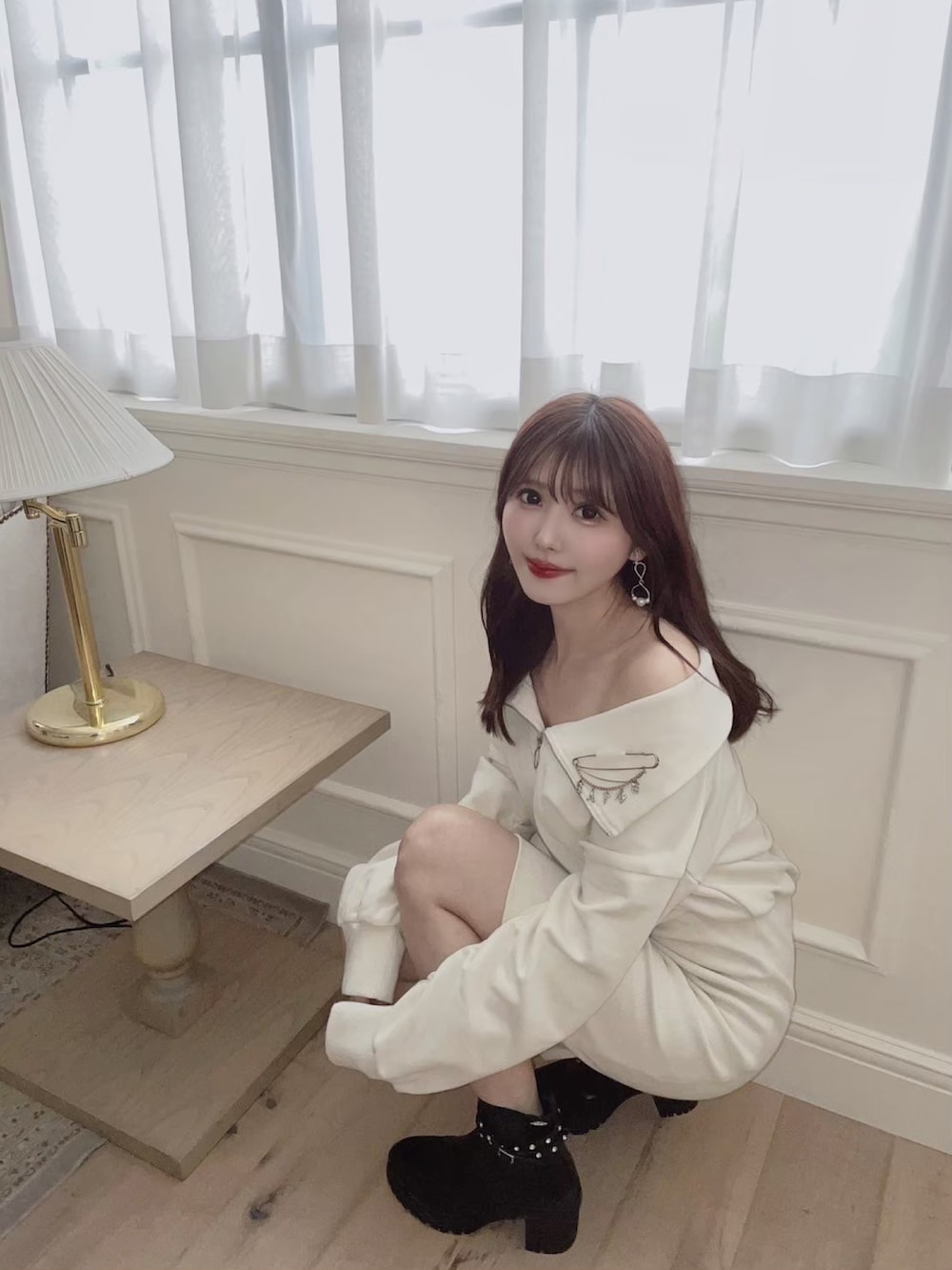 ホワイト系のワンピース、ブラック系のブーツ、シルバー系のブローチ/コサージュを着用したレディースの秋コーディネートの3枚目の写真