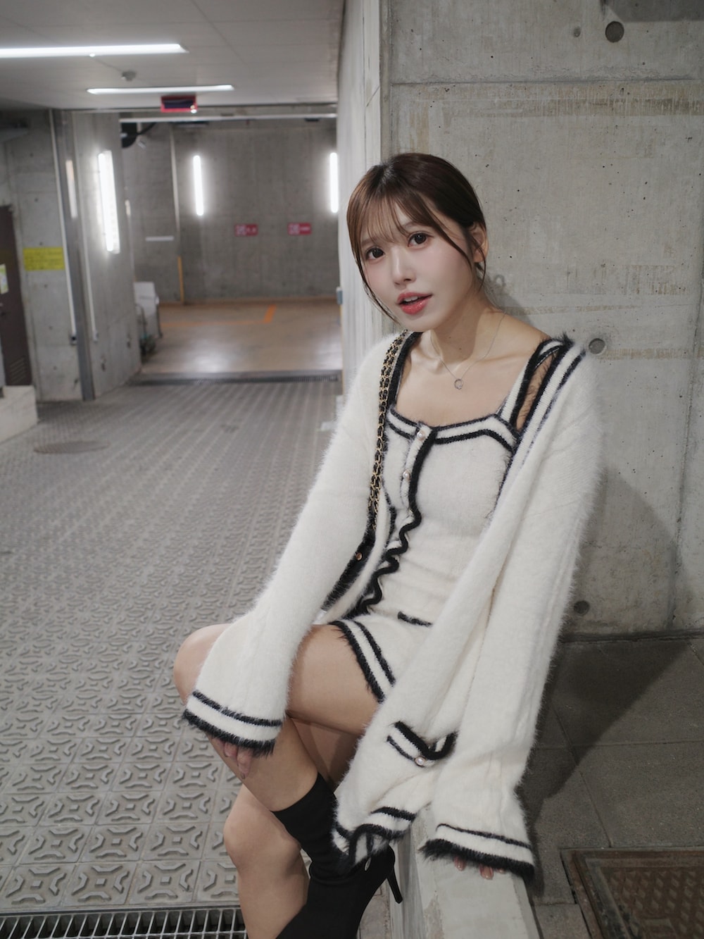 ホワイト系のワンピース、ブラック系のブーツ、ブラック系のハンドバッグを着用したレディースの秋コーディネートの2枚目の写真