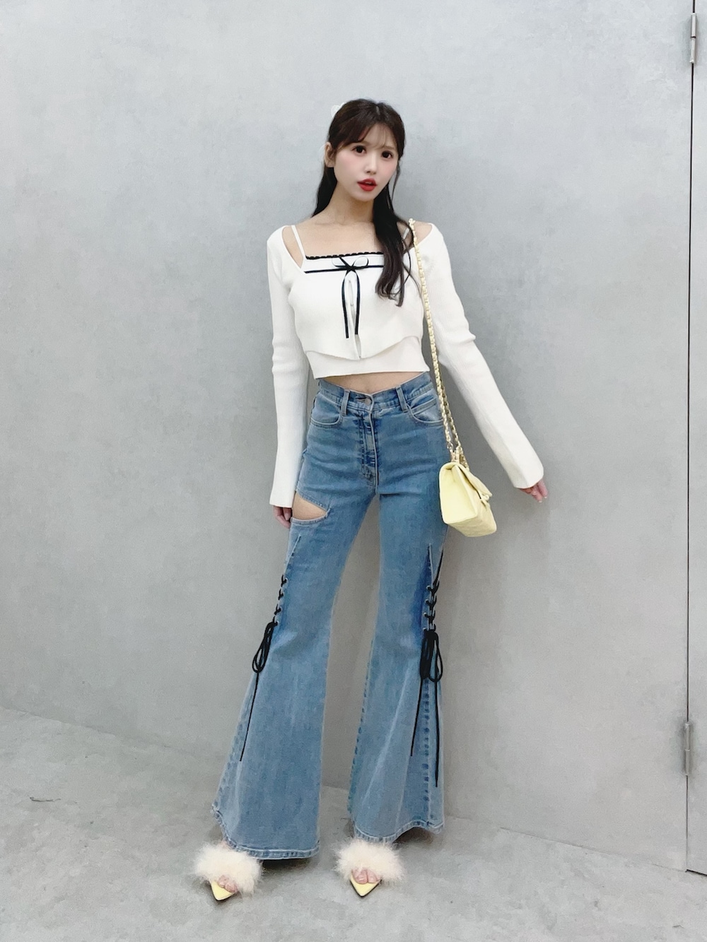 ホワイト系のニット/セーター、イエロー系のサンダル、ブルー系のデニムパンツを着用したレディースの冬コーディネートの3枚目の写真