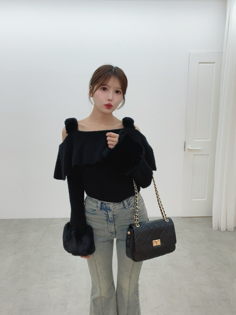 ブラック系のハンドバッグ、ブルー系のデニムパンツ、ブラック系のニット/セーターを着用したレディースの秋コーディネートの8枚目の写真