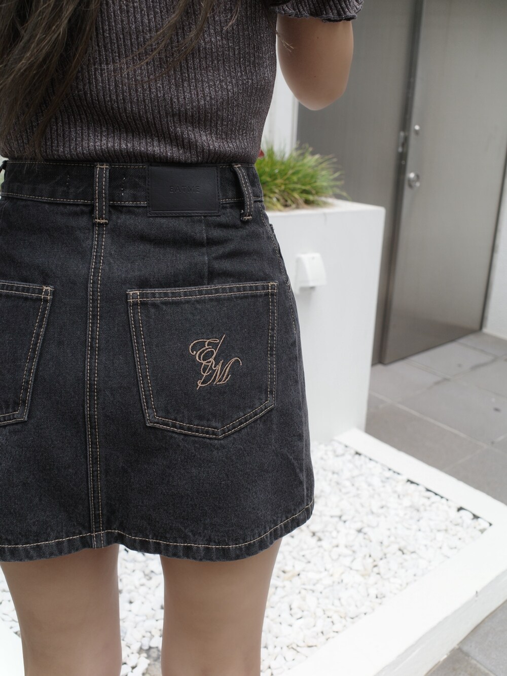 ブラック系のデニムスカート、ブラック系のサンダル、グレー系のTシャツ/カットソーを着用したレディースの夏コーディネートの10枚目の写真