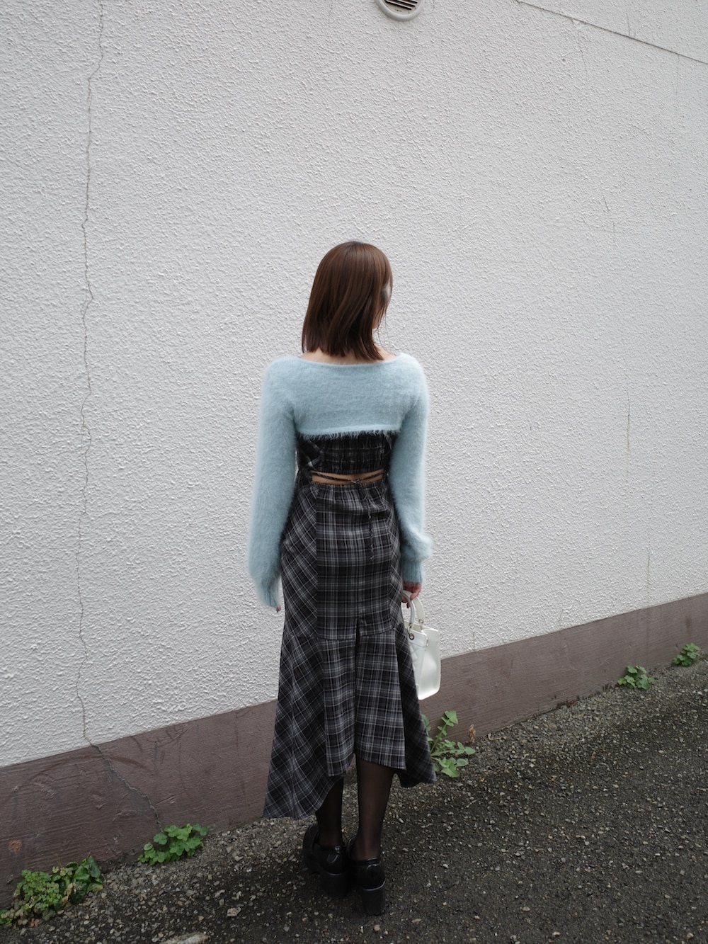 ブルー系のニット/セーター、ホワイト系のハンドバッグ、ブラック系のワンピースを着用したレディースの秋コーディネートの4枚目の写真